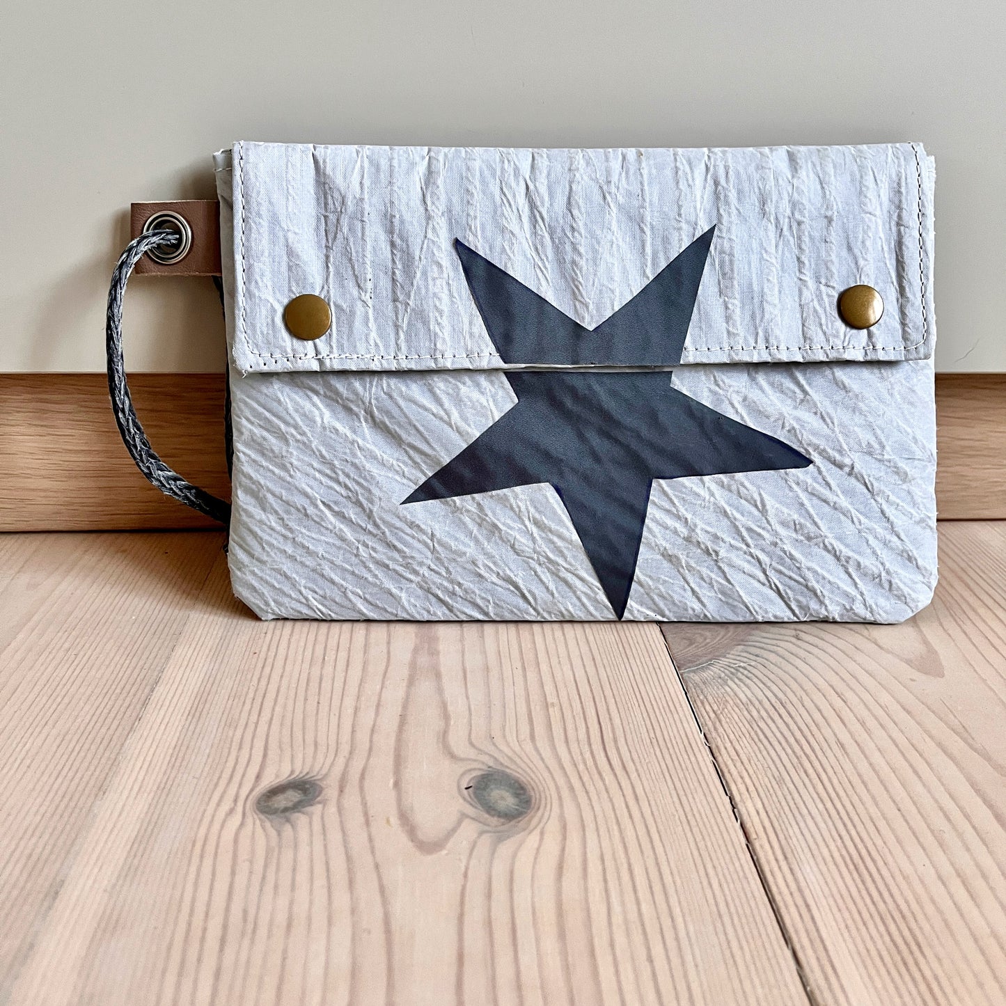 Liten clutch, med grå stjerne, og klaff. Grått Hanse-seil.